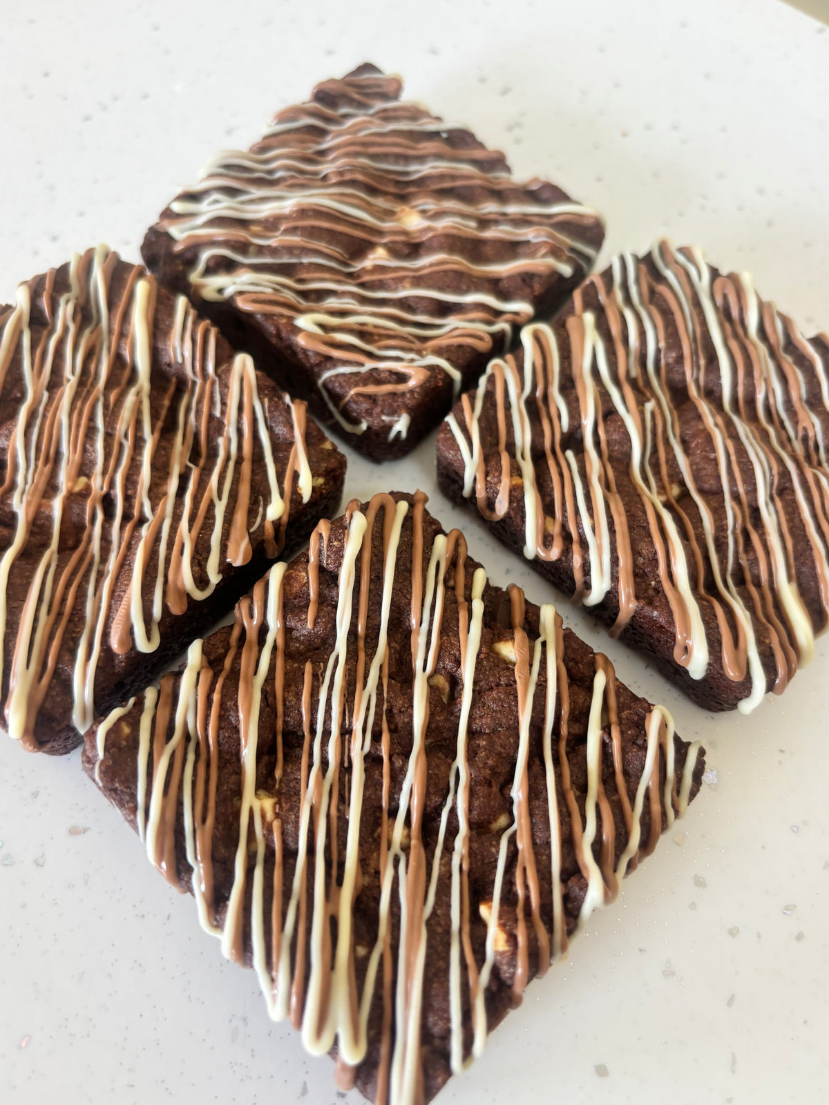Triple chocolate cookie packed with white, milk and dark chocolate, finished with a milk and white chocolate drizzle